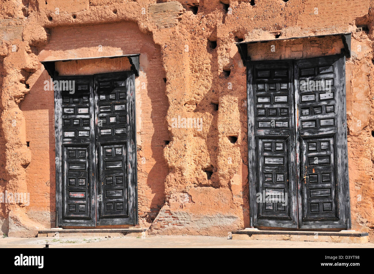 Coppia di vecchie porte grigio impostato in alcune delle restanti pareti mudbrick dell antica El Badii Palace, Marrakech, Marocco Foto Stock