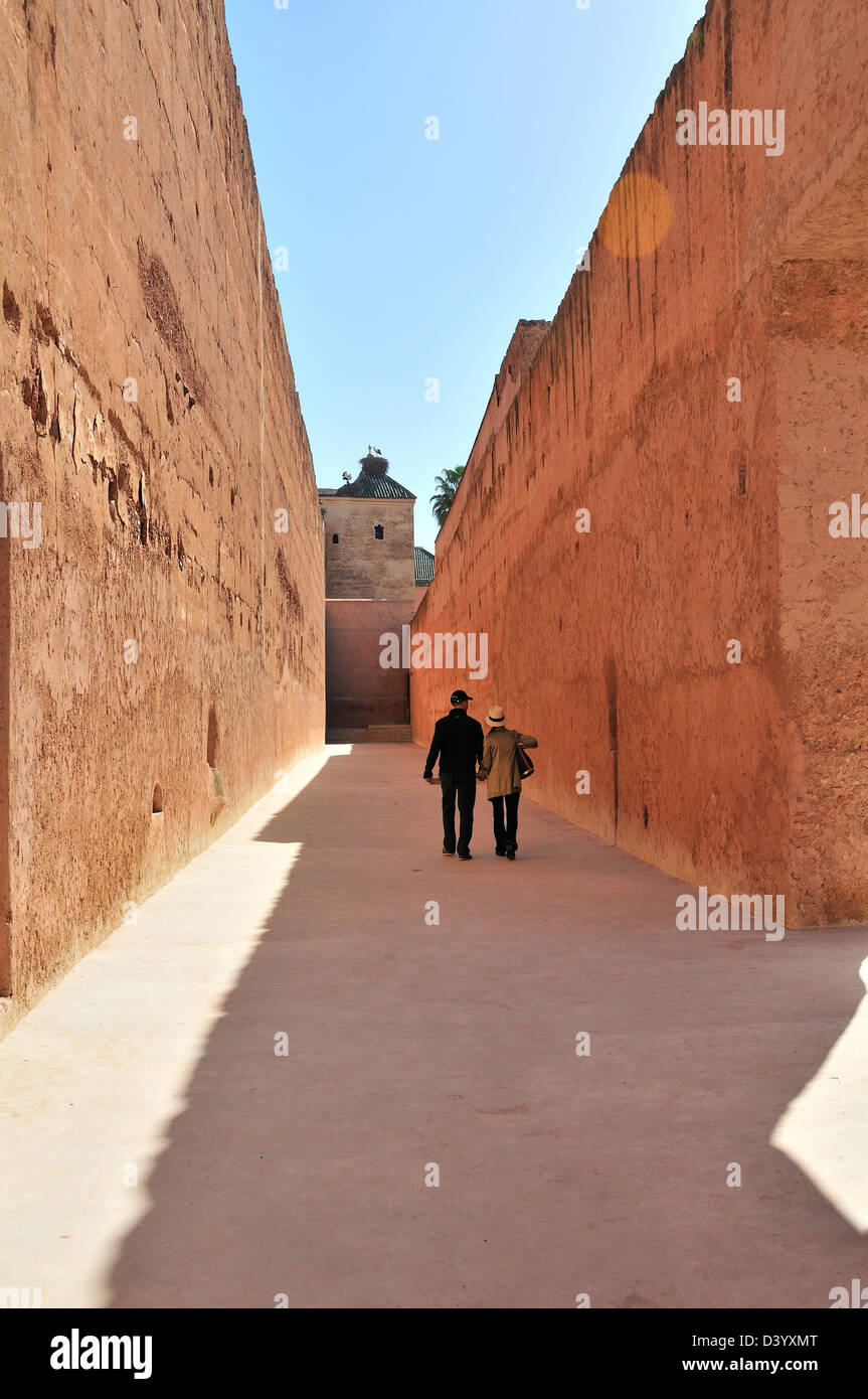 Vista posteriore della coppia giovane camminando tra due antiche tinte di rosa alte mura a El Badii Palace, Marrakech, Marocco Foto Stock
