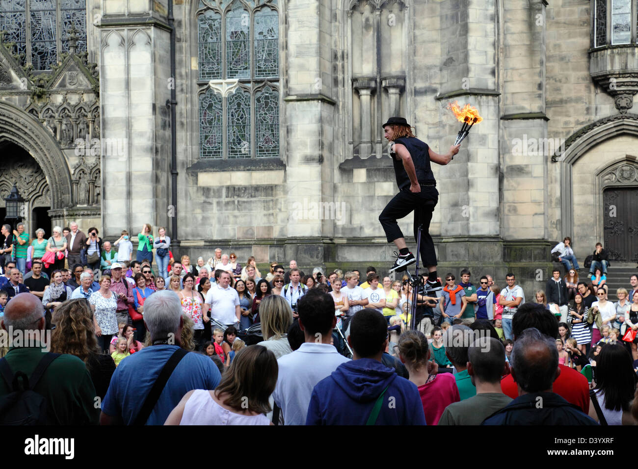 Edinburgh Festival Fringe Street performer Damien Ryan, mortale serio, intrattenere una folla che giocolano con il fuoco su un ciclo uni, Scozia, Regno Unito, Europa Foto Stock