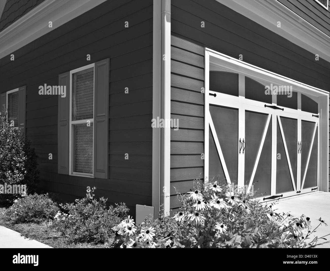 L'angolo di una casa che mostra le porte di garage e di finestre con persiane. Foto Stock