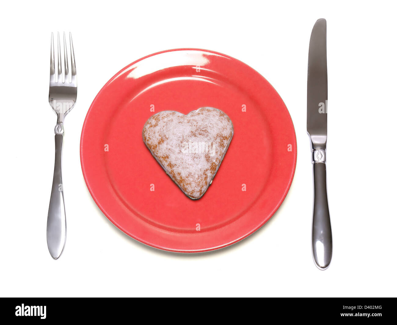 A forma di cuore torta di panpepato sulla targhetta rossa con coltello e forchetta su sfondo bianco Foto Stock