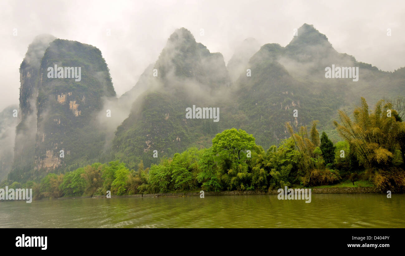 Nuvole Low-Lying Sindone affioramenti calcarei su un Drizzly giorno - il Fiume Li, Guilin, Cina Foto Stock
