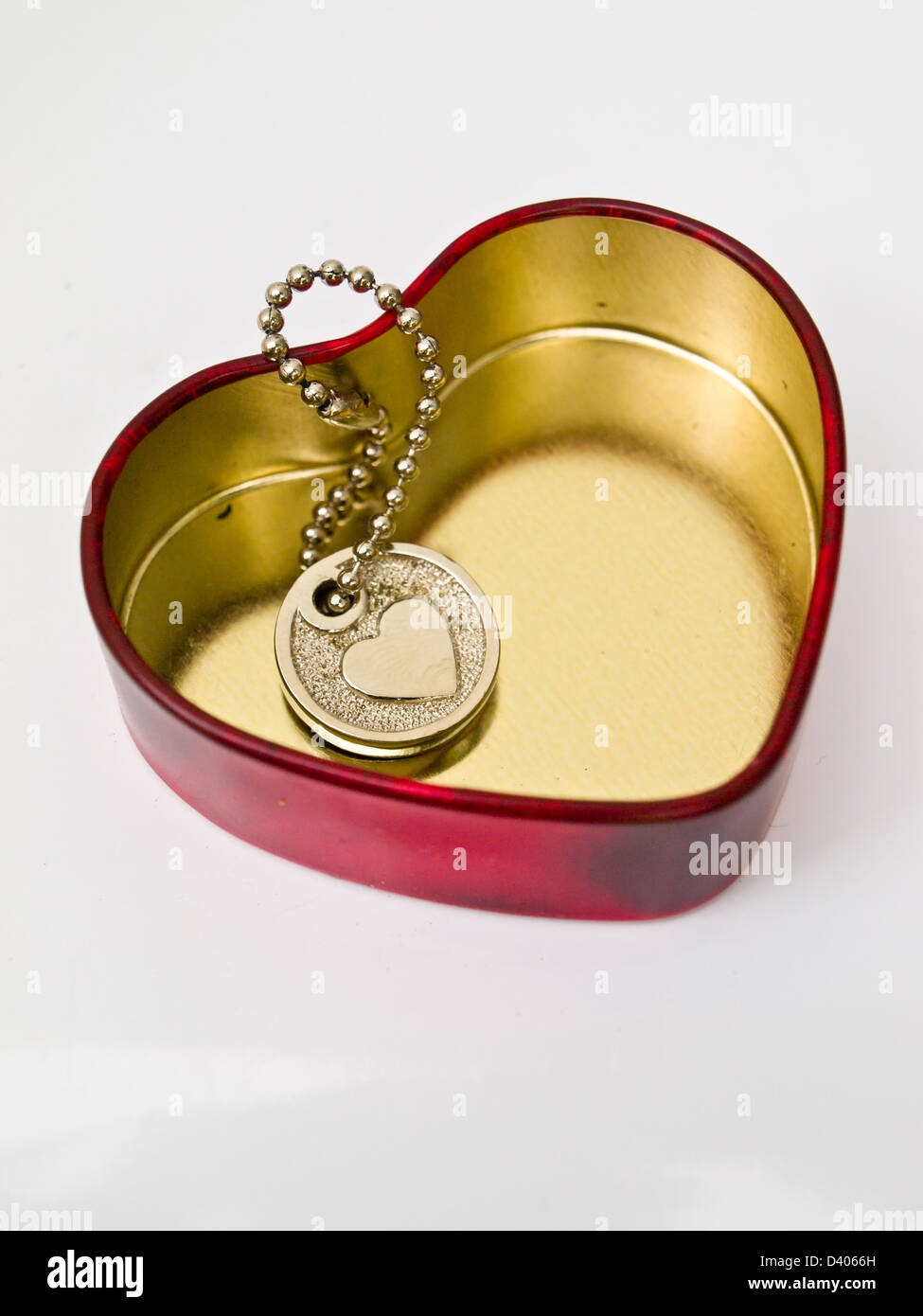 Un cuore in miniatura chiave a catena in un cuore rosso in acciaio inox box, un simbolo universale di amore Foto Stock