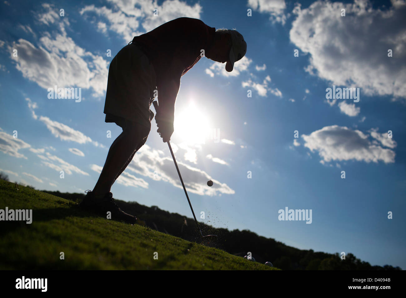 Un golfista senior piazzole su un verde a un campo pratica da golf gamma. Foto Stock