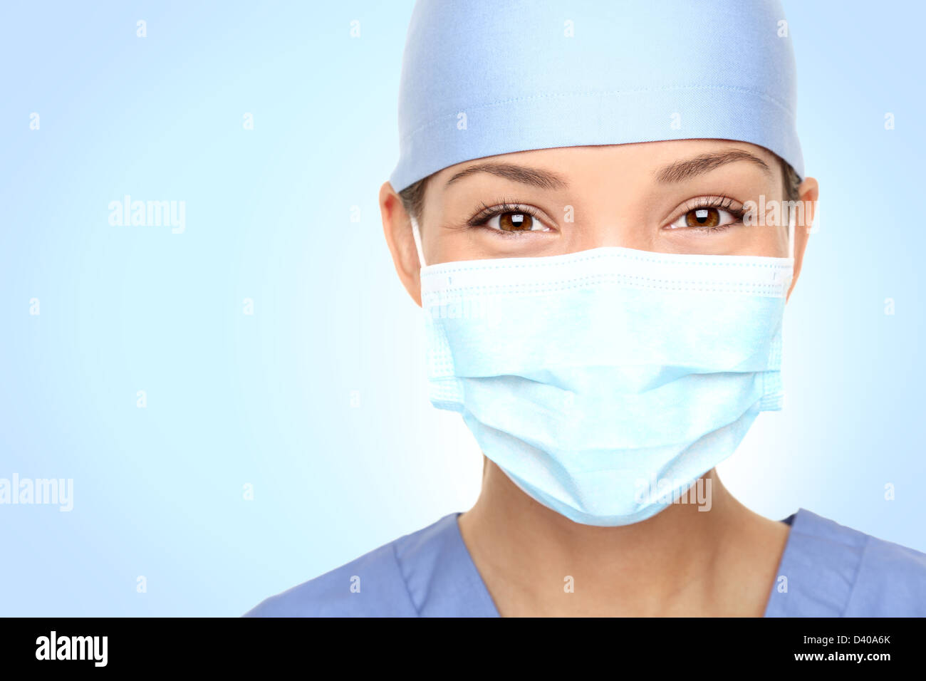 Closeup ritratto di giovani asiatici femmina caucasica medico / infermiere sorridente dietro la maschera di chirurgo Foto Stock