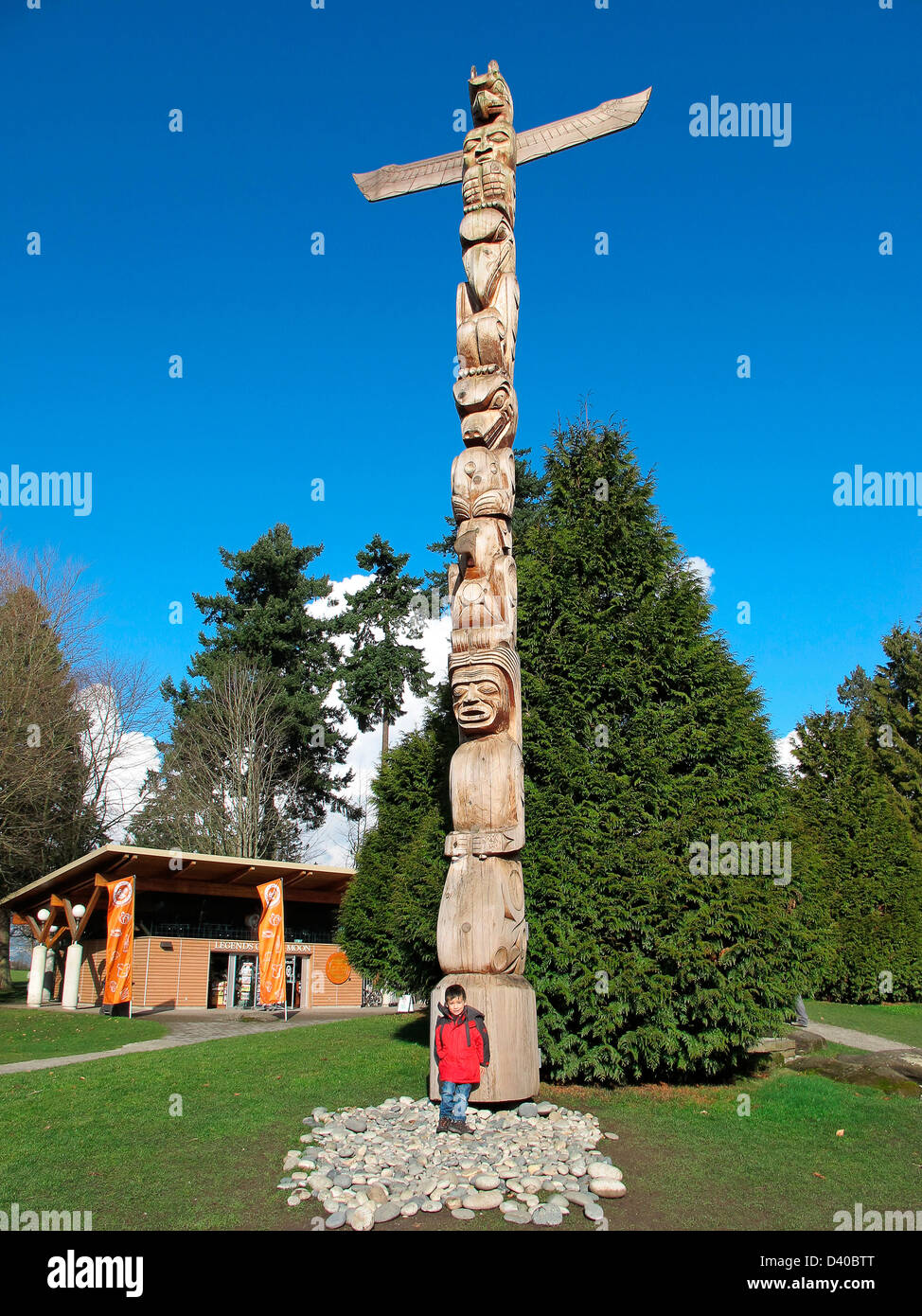 Ragazzo in piedi accanto al totem pole. Foto Stock