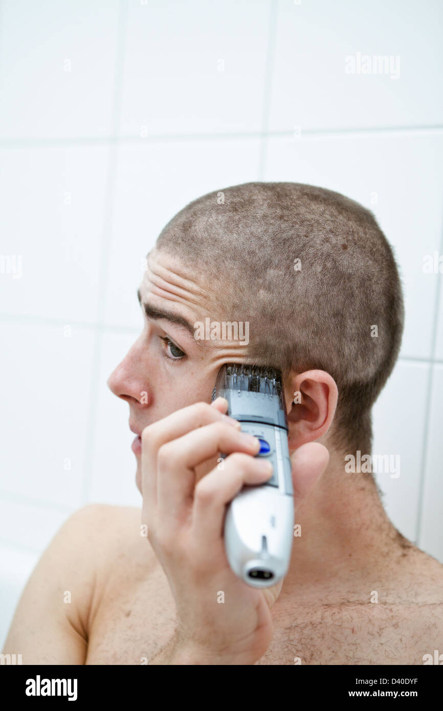 Giovane uomo caucasico facendo propria buzzcut dalla testina di rasatura  con rasoio elettrico clipper Foto stock - Alamy