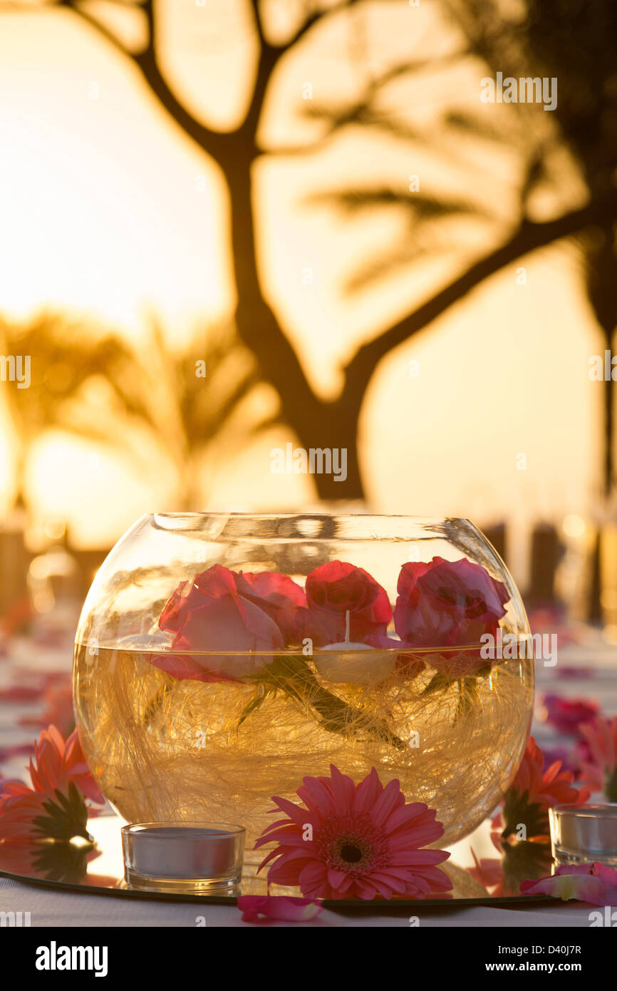 Tabella romantico centrotavola con ciotola e fiori nel sole di sera all'esterno. Foto Stock