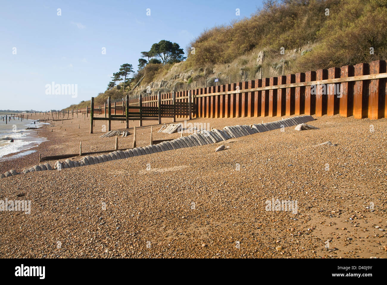 Acciaio arrugginito palificate mare difese a parete e ciottoli vicino Bawdsey Quay, Suffolk, Inghilterra Foto Stock