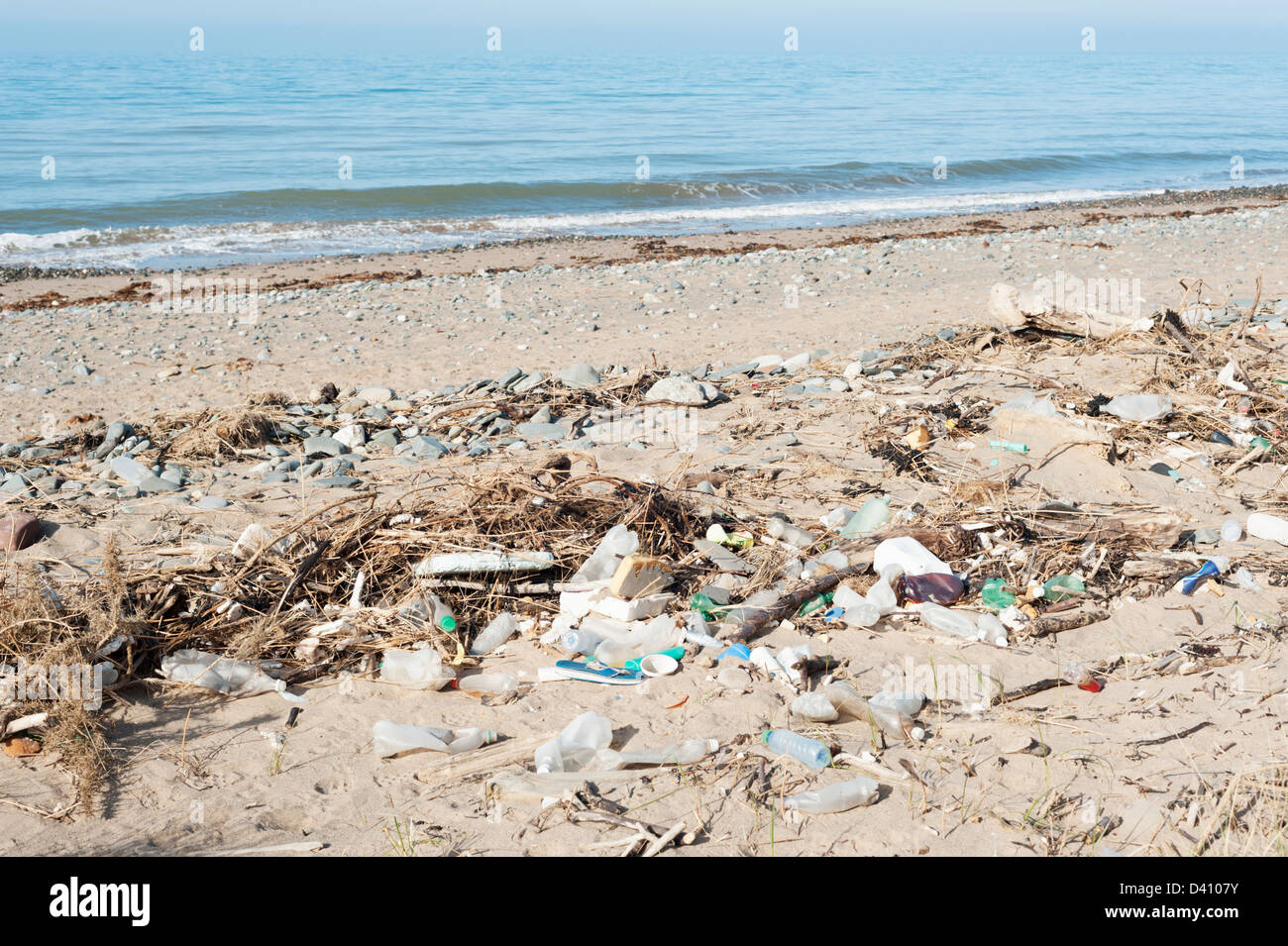 Bottiglie di plastica e di altri rifiuti e rifiuti lavato fino a una sporca British beach Foto Stock