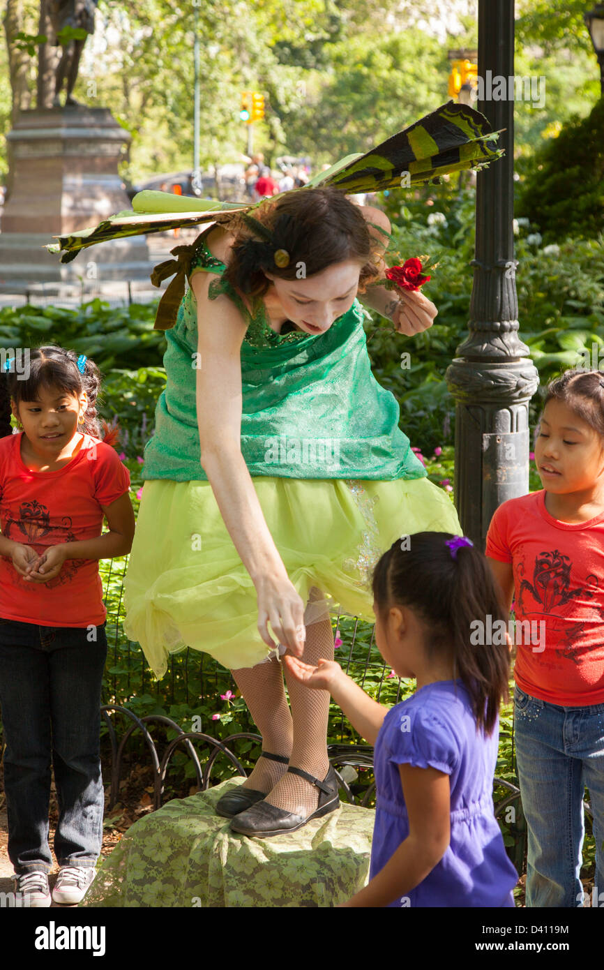 3 ragazze giovani interagire con una strada Performer di Central Park di New York City, Stati Uniti d'America Foto Stock