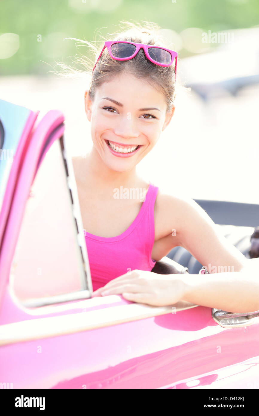 Ritratto di giovane e bella gara di misto donna in rosa vecchia auto retrò sorridente in estate Havana, Cuba Foto Stock