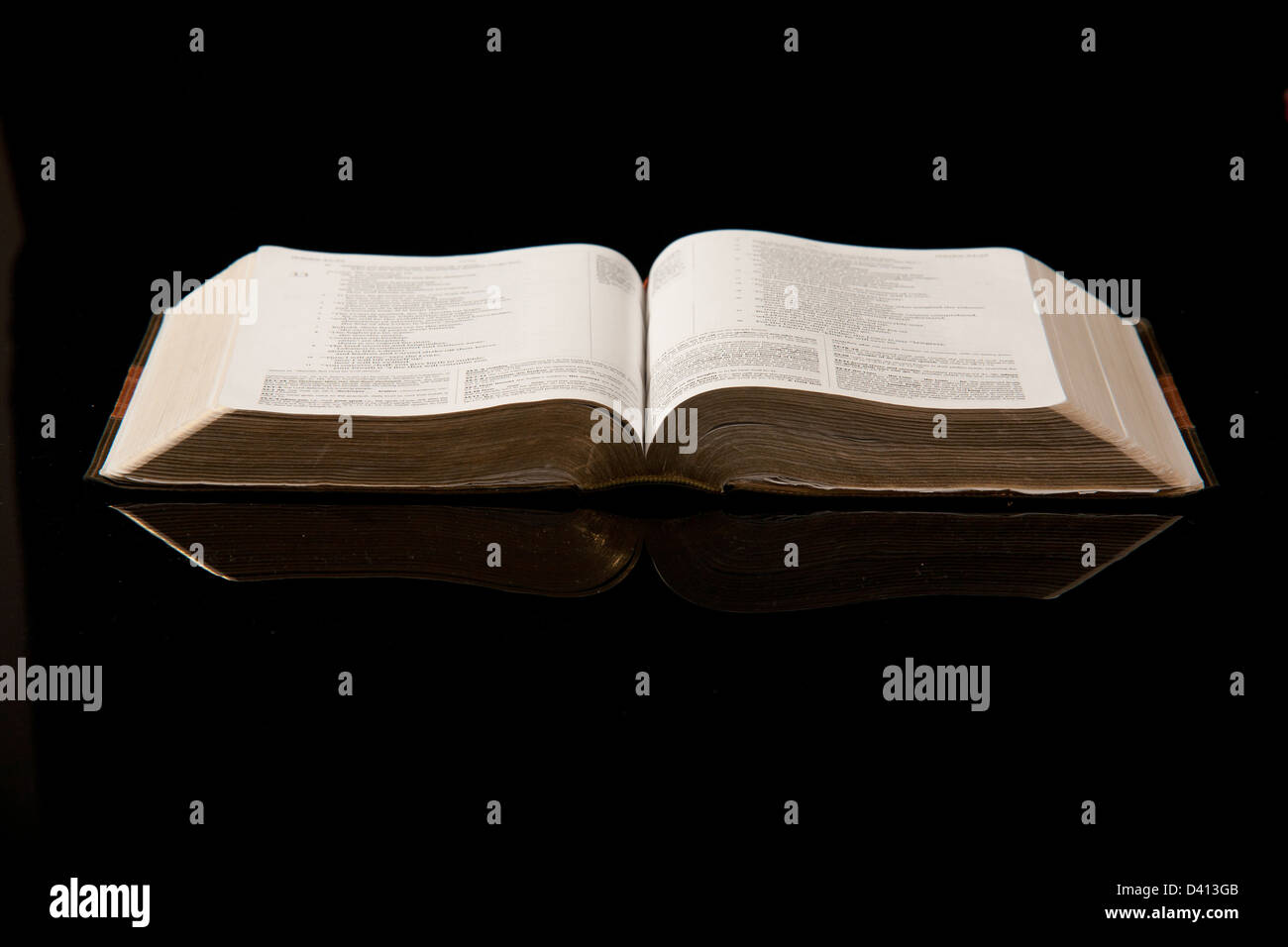 Un aprire la Bibbia insieme contro uno sfondo nero. Foto Stock
