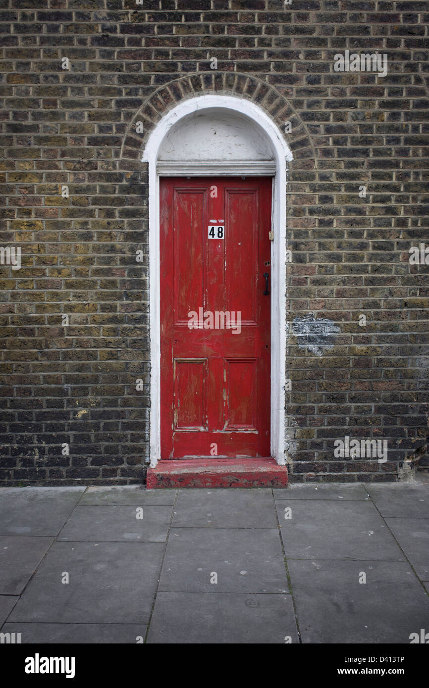 Una scarsa manutenzione porta rossa con il numero 48, di un vecchio edificio vittoriano nel nord di Londra quartiere di Kings Cross. Questa zona di Londra nord è attraversata la strada dalla stazione principale dove i visitatori europei arrivano sul Eurostar dall'Europa continentale e la King Cross area è impostato per una riqualificazione così il futuro per questa architettura originale è incerta. Foto Stock