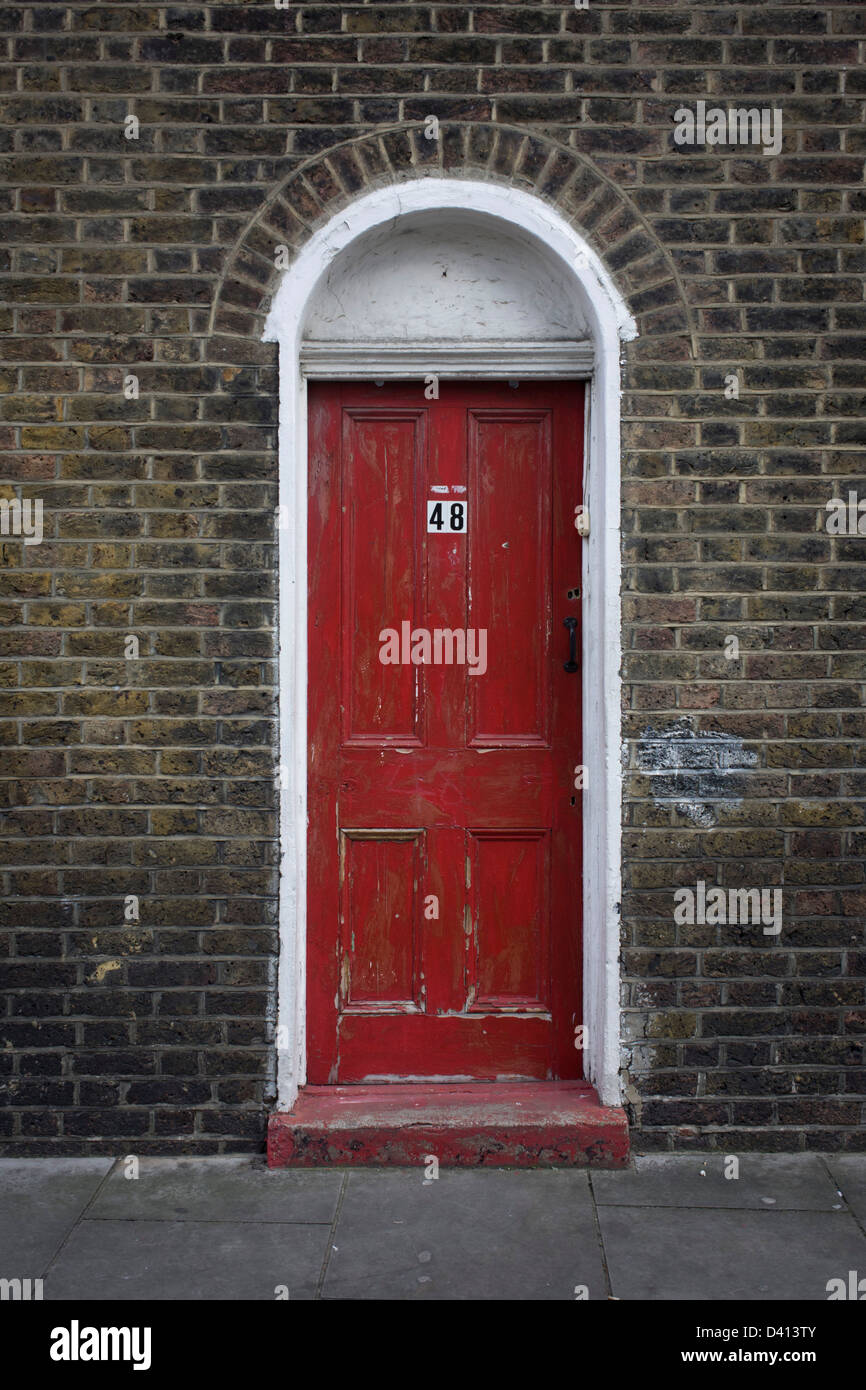 Una scarsa manutenzione porta rossa con il numero 48, di un vecchio edificio vittoriano nel nord di Londra quartiere di Kings Cross. Questa zona di Londra nord è attraversata la strada dalla stazione principale dove i visitatori europei arrivano sul Eurostar dall'Europa continentale e la King Cross area è impostato per una riqualificazione così il futuro per questa architettura originale è incerta. Foto Stock