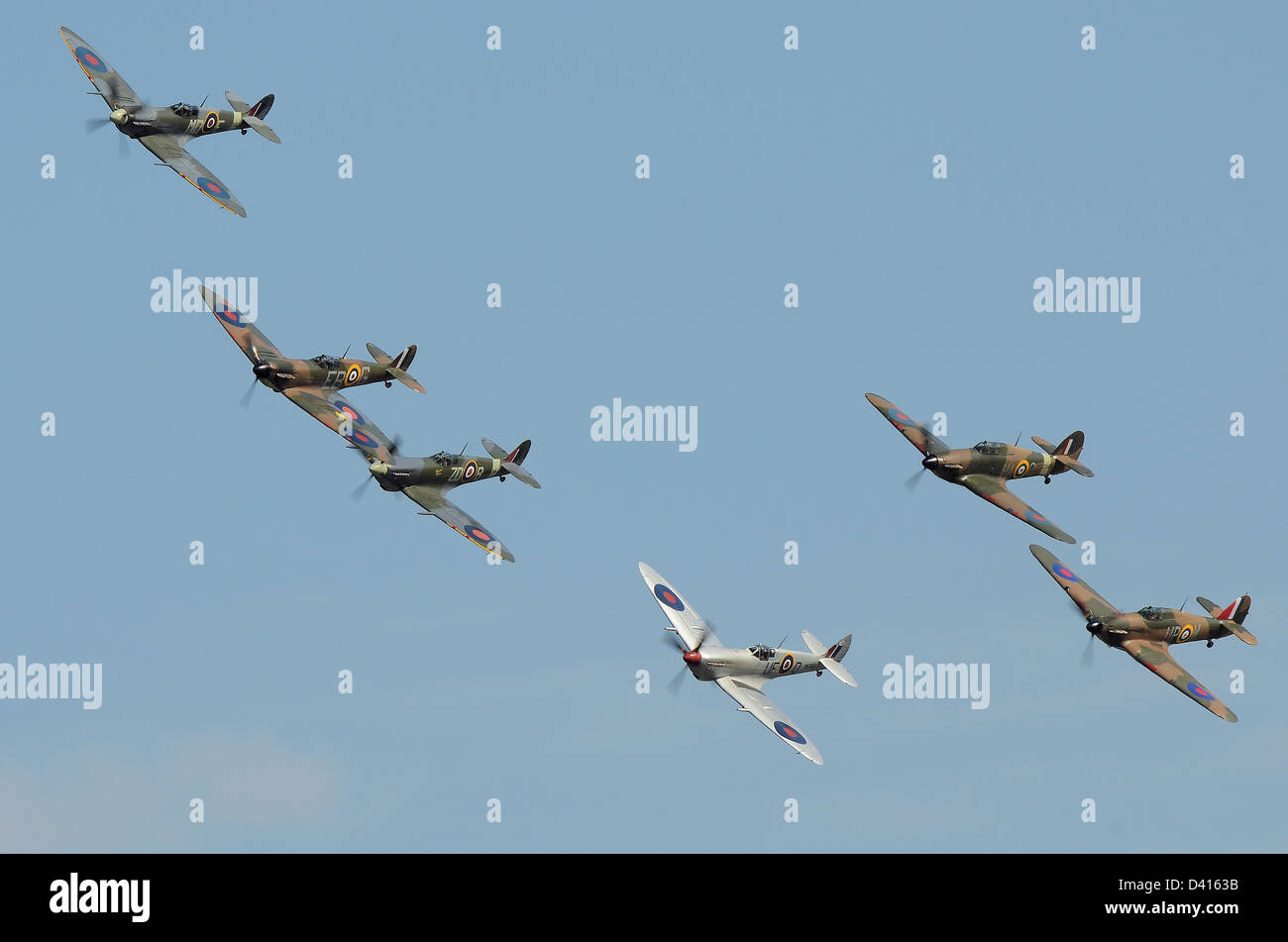 Gli Spitfire e gli Hurricane della RAF si abbattono come se attaccassero in uno scenario bellico della Battaglia d'Inghilterra nel cielo blu. Aerei della seconda guerra mondiale che volano all'aerodromo Foto Stock