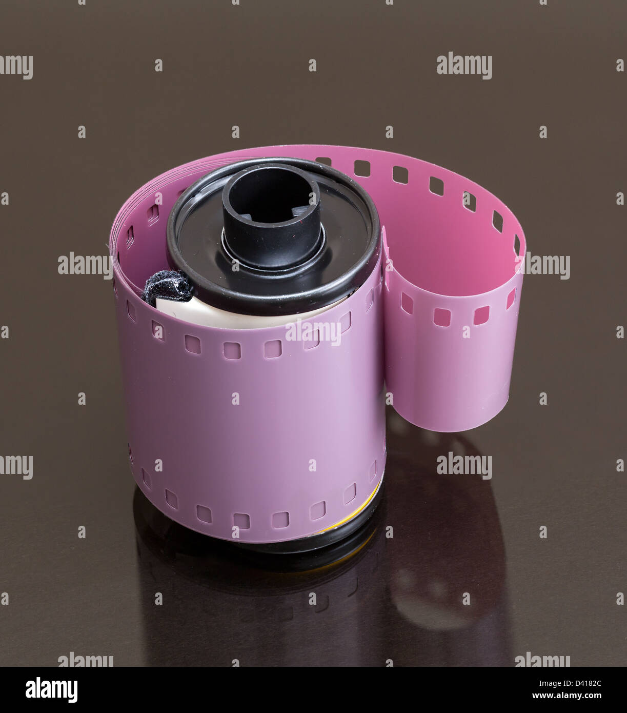 Immagine macro di pellicola 35mm canister con negativo a spirale sulla superficie riflettente Foto Stock