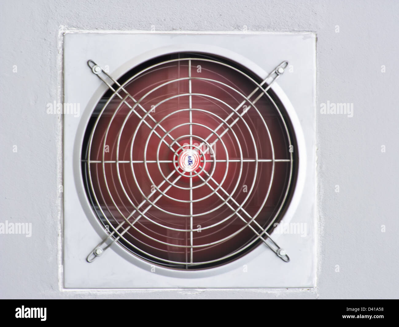 Un rosso ventilato industriale ventola sul muro grigio come sfondo Foto Stock