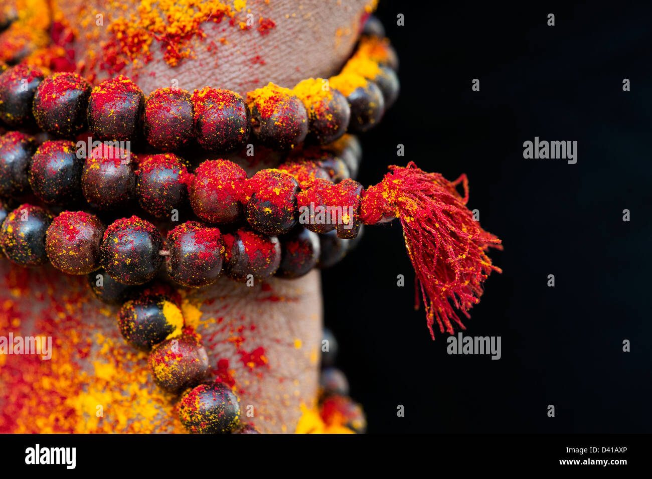 Japa Mala i grani di preghiera intorno a un Indiano mans lato rivestito con polvere colorata. India Foto Stock