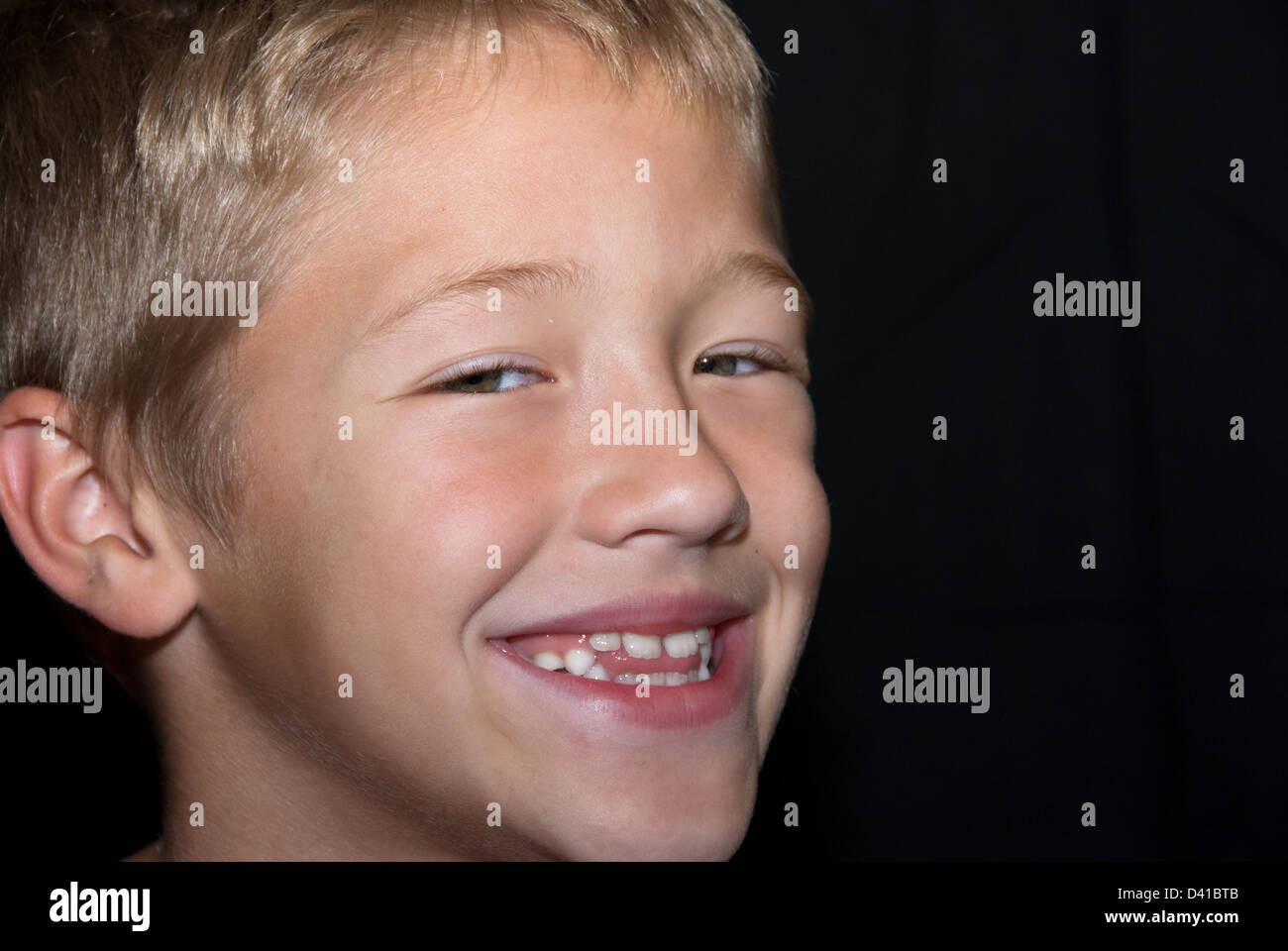 Sorridente e felice ragazzo su sfondo nero. Foto Stock