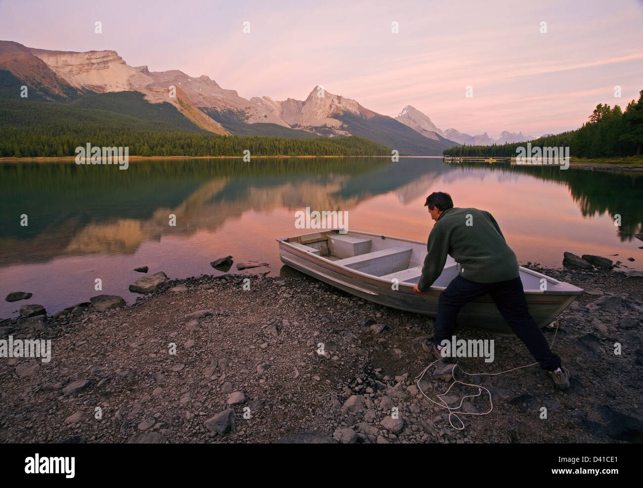 Metà maschio età tirando verso l'alto riga barca sulla riva del Lago Maligne, Jasper National Park, Alberta, Canada. Foto Stock
