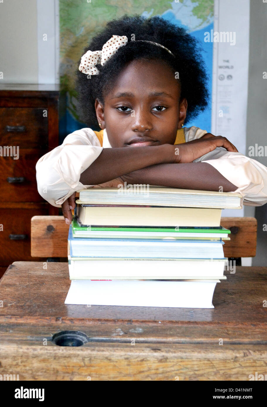 Un po' di black schoolgirl appoggiata su una pila di libri. Foto Stock