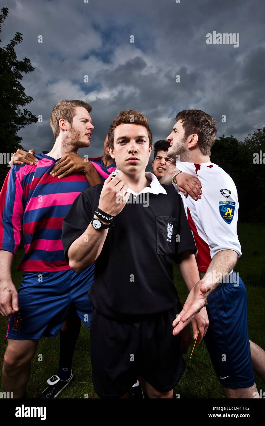 Arbitro con red card con arrabbiato giocatori di calcio Foto Stock