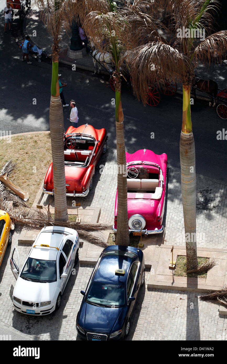 La vecchia e la nuova auto taxi parcheggiato nel centro di Avana Cuba in attesa di turisti al di fuori della struttura Iberostar Parc Central Hotel Foto Stock