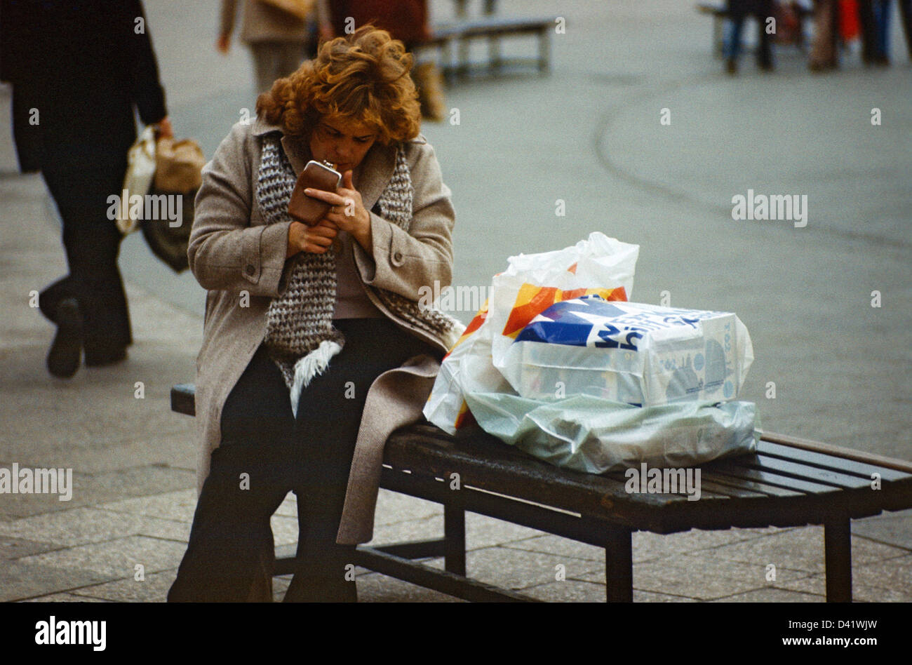 Berlino, gdr, donna seduta su una panchina e costruiti una sigaretta Foto Stock