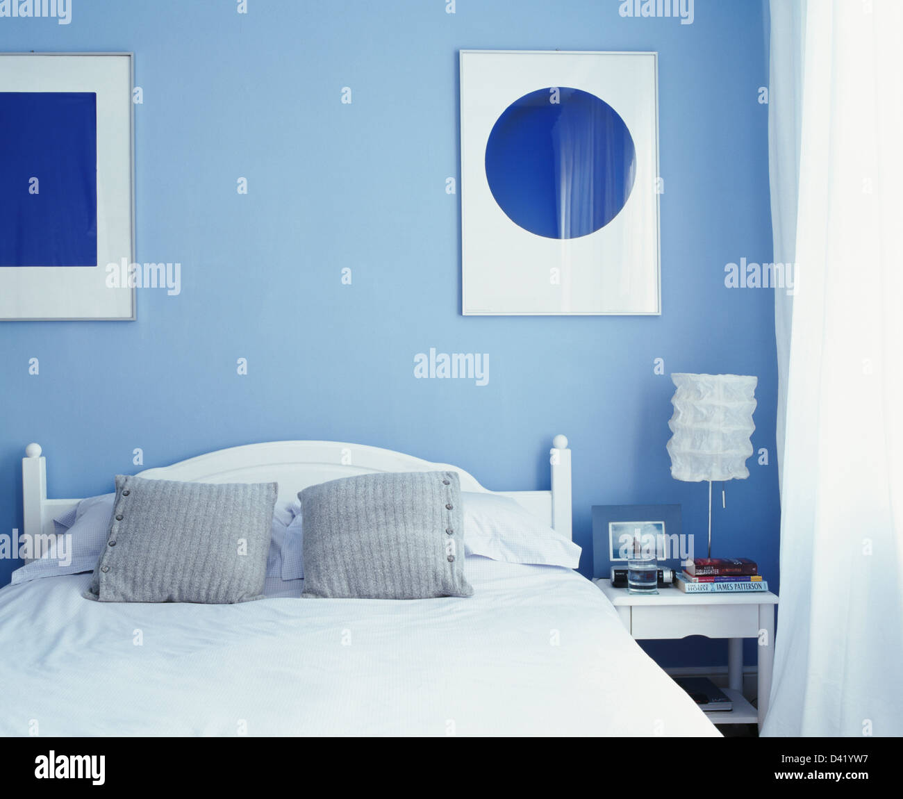 Abstract foto sopra il letto con cuscini di colore grigio in blu pallido stile economia moderna camera da letto con la lampada bianca sul comodino Foto Stock