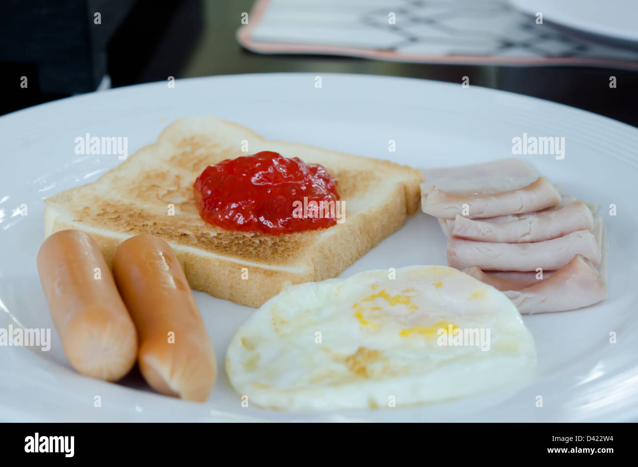 Il cibo sulla piastra bianca (pancetta, uova fritte , salsiccia , toast e marmellata) Foto Stock