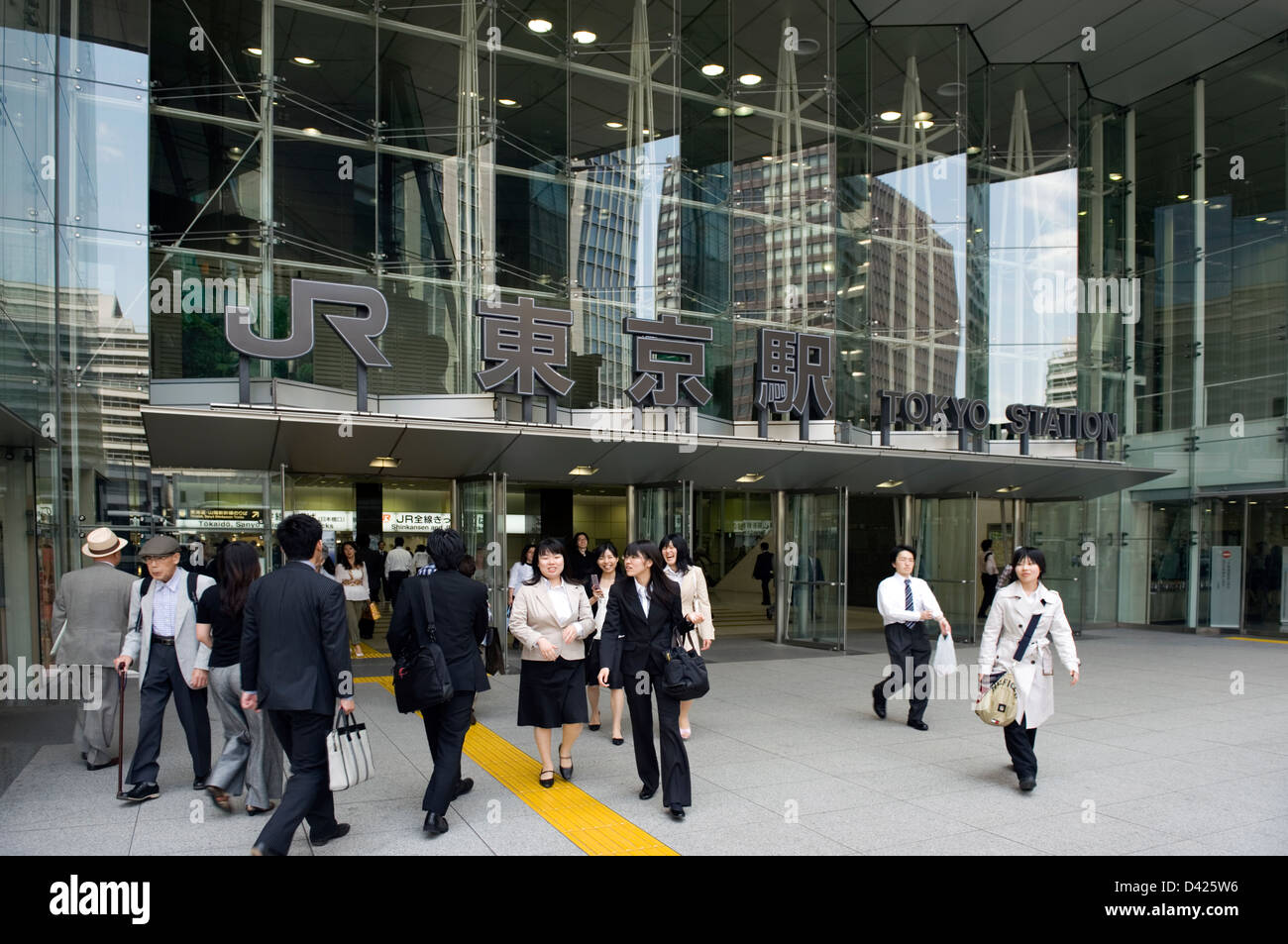Uomini d'affari e ufficio onorevoli colleghe che entrano e lasciano un moderno, nuovo in vetro e acciaio ingresso al Giappone (ferroviaria JR) Stazione di Tokyo. Foto Stock
