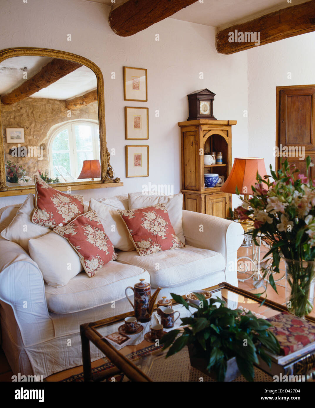 Grande specchio sopra divano bianco con rosa+cuscini bianchi nel paese  francese soggiorno Foto stock - Alamy