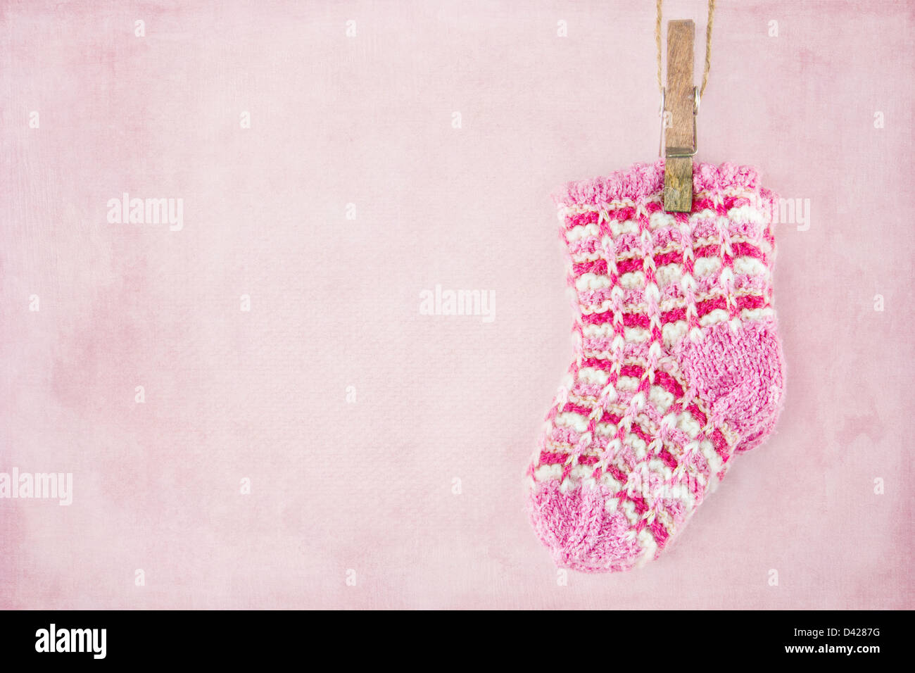 Baby girl alle calze di lana sul pastello testurizzata sfondo rosa Foto Stock