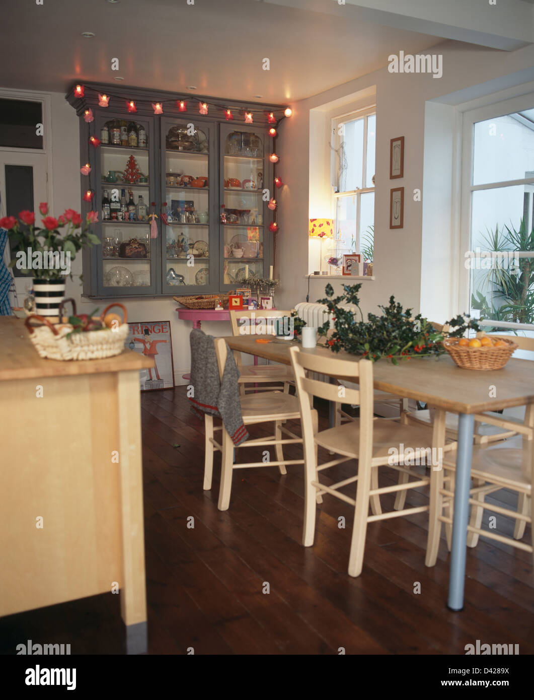 Le luci di Natale in vetrina armadietto pensile in cucina con parquet in  legno di quercia e con holly su semplice tavolo in legno Foto stock - Alamy