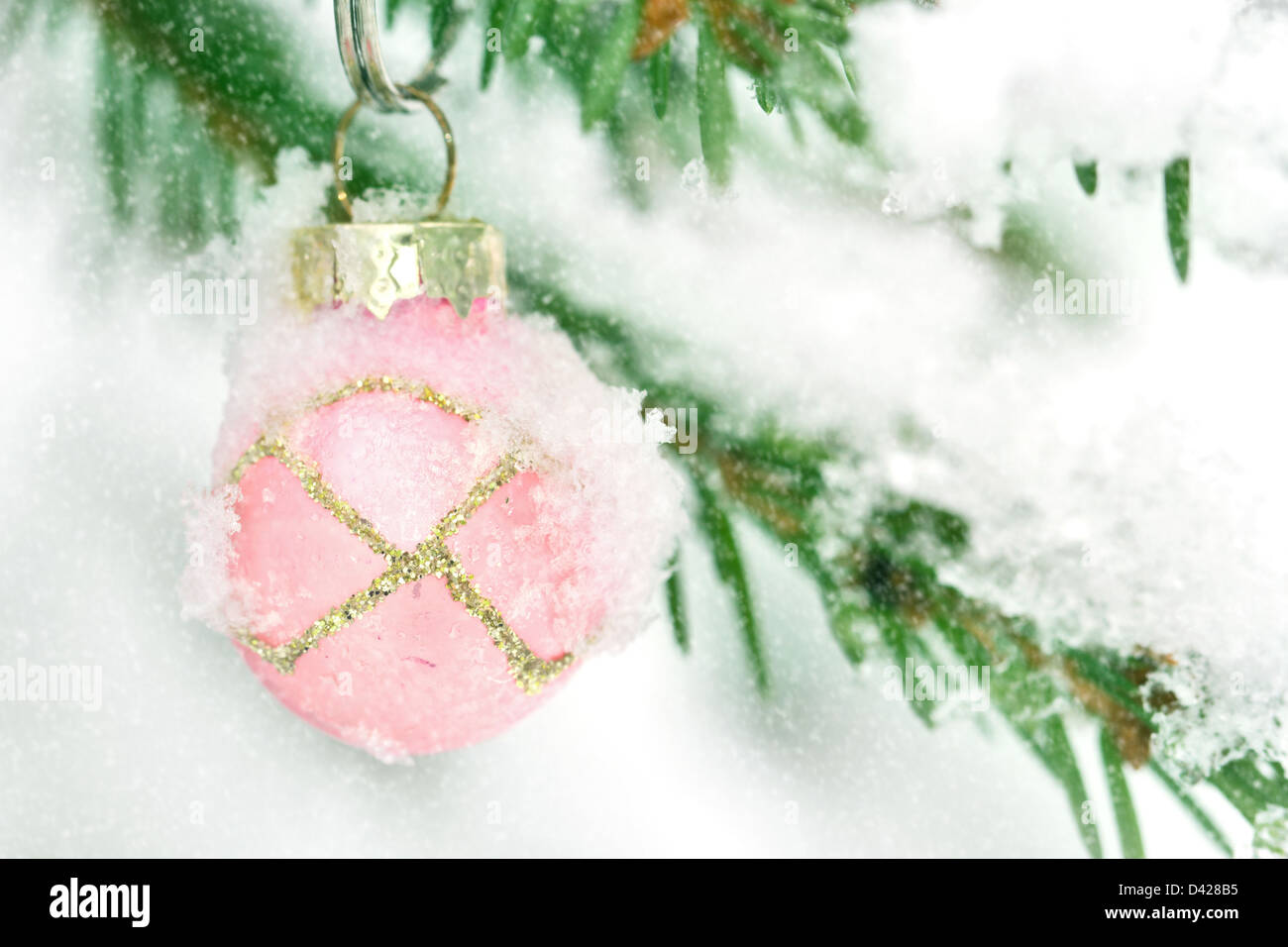 Rosa Pallina natale appeso all'aperto in un snowy albero di Natale Foto Stock