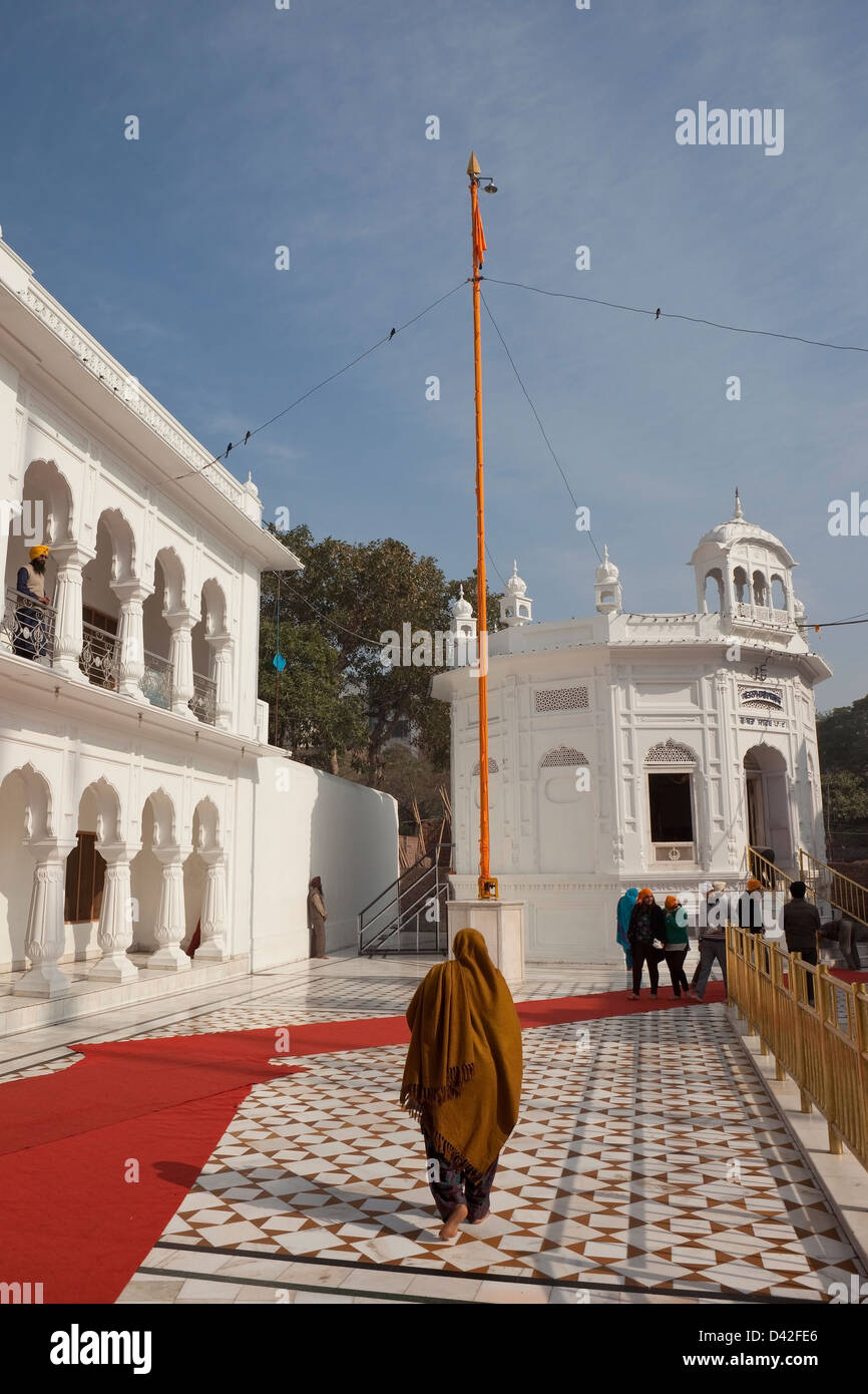 Una donna pellegrino a piedi lungo i pavimenti di marmo all'interno del tempio d'oro complesso Amritsar Punjab India Foto Stock