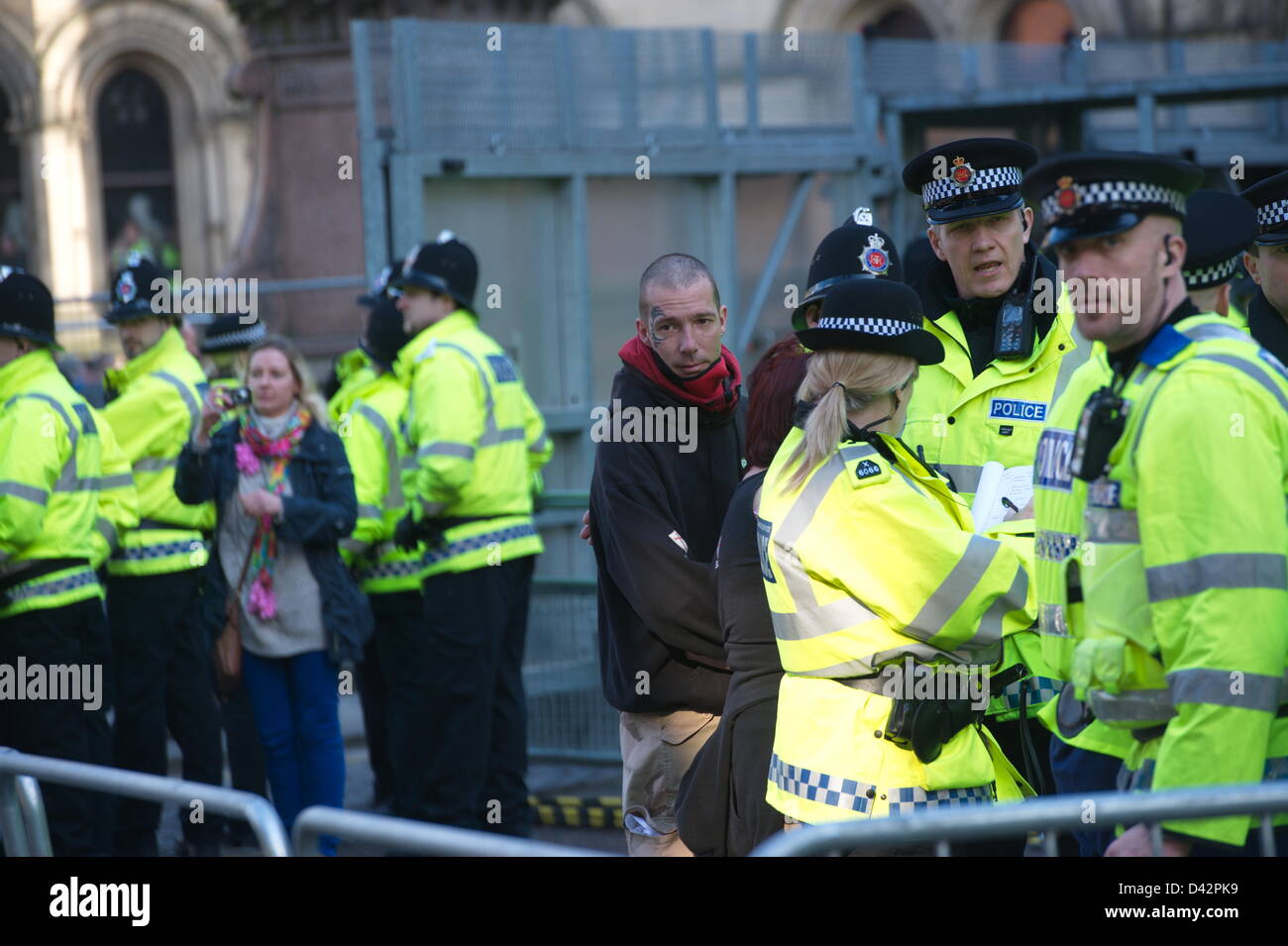Tatuaggio di fronte l uomo è scortato fuori dell'EDL area di mantenimento da parte di un certo numero di funzionari di polizia. Dimostrazione passa su off in modo relativamente pacifico - con una massiccia operazione di polizia mantenendo più a destra della Difesa inglese League (EDL) sostenitori e avversari, guidato da unirsi contro il fascismo (UAF), oltre che come hanno fatto convergere su Albert Square. Manchester, Inghilterra, Regno Unito. Sabato 2 marzo 2013 Foto Stock