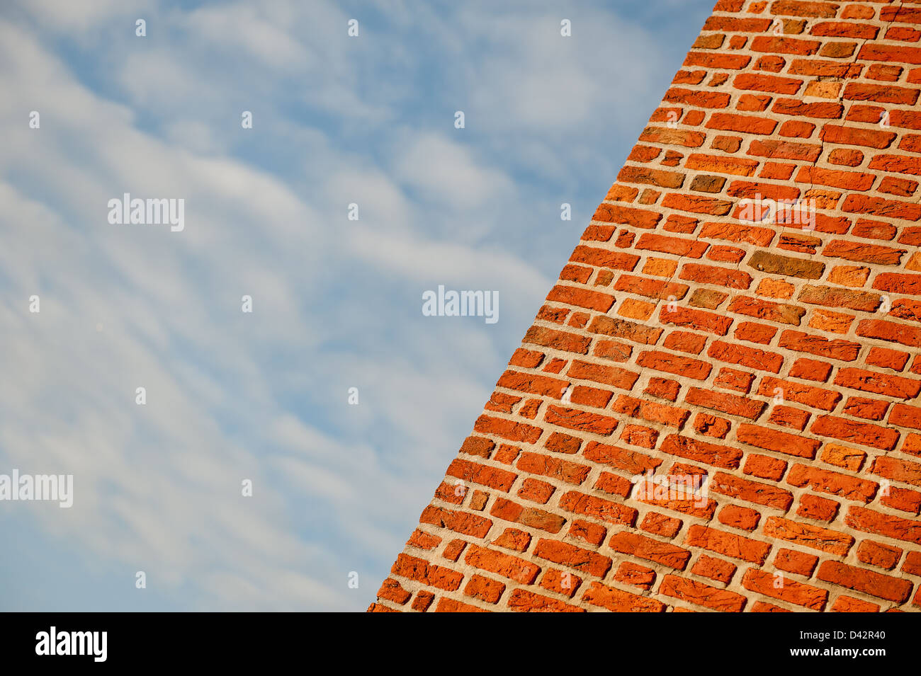 Angolo di visualizzazione di un rosso un muro di mattoni con un cielo blu con nuvole. Foto Stock
