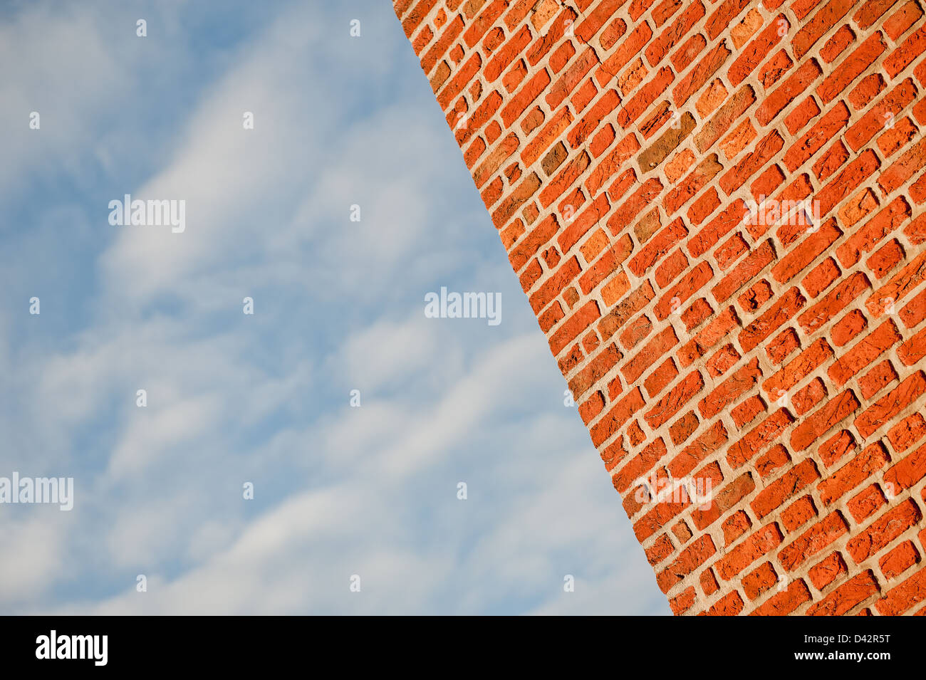 Angolo di visualizzazione di un rosso un muro di mattoni con un cielo blu con nuvole. Foto Stock