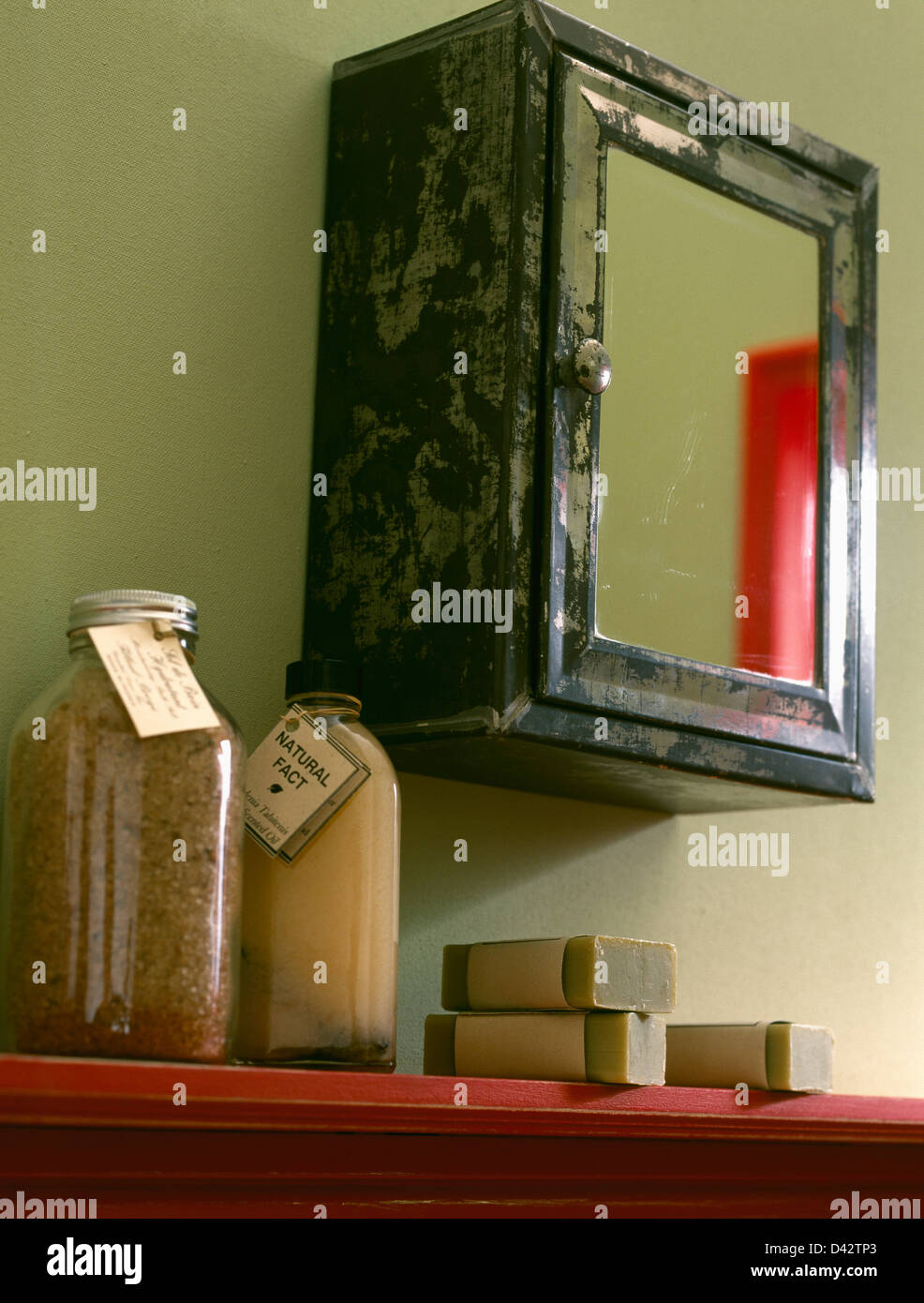 Close-up di vintage specchiata mobiletto del bagno al di sopra di uno scaffale con fatti in casa a base di sali da bagno e saponi Foto Stock