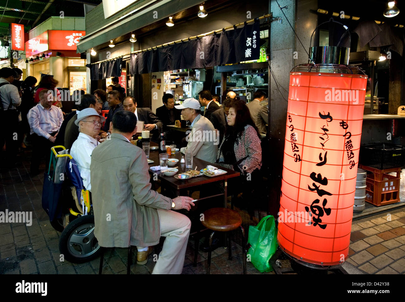Patroni godendo un fine pasto al ristorante sul marciapiede sotto i binari ferroviari nel quartiere degli intrattenimenti di Okachimachi, Tokyo. Foto Stock