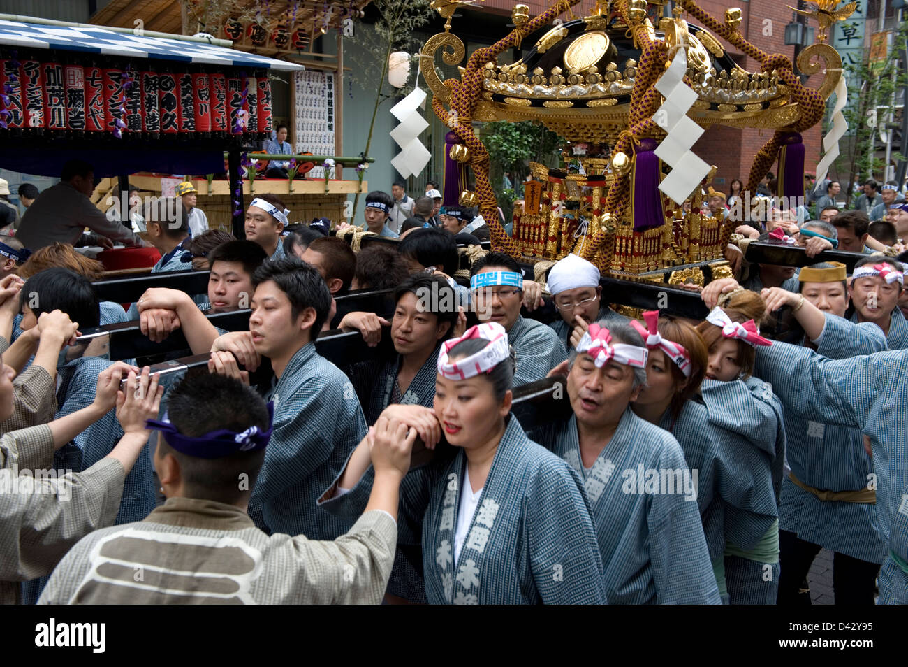 Gli uomini e le donne portano un oro decorate mikoshi sacro santuario portatile in Sanja Matsuri Festival, uno dei Tokyo Big tre festività Foto Stock