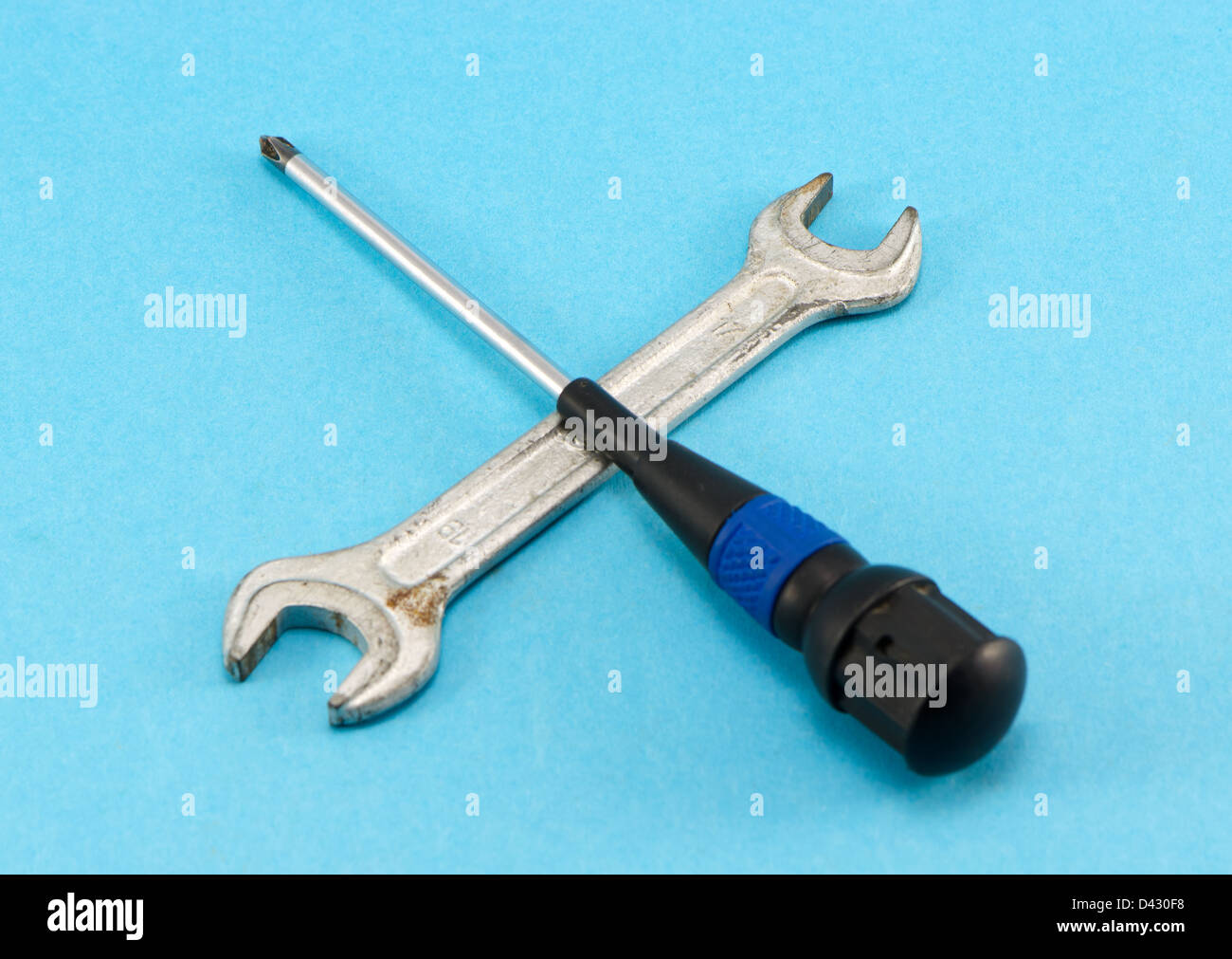 Un cacciavite ruotare la vite-chiave chiave tommy costruzione utensili di lavoro incrociati su sfondo blu. Foto Stock