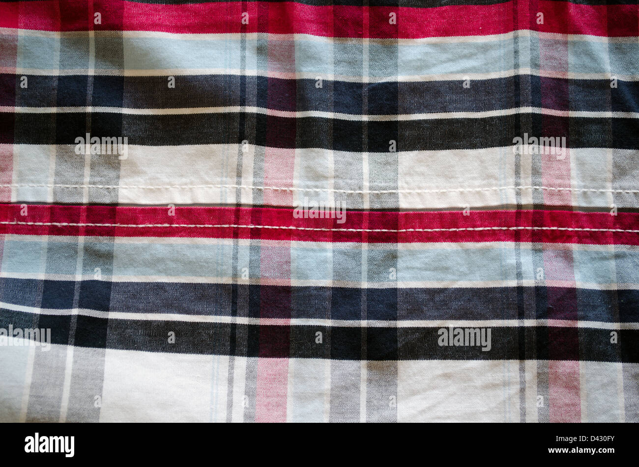 Primo piano della camicia in tessuto di cotone di materiale e forma quadrata rosso blu nero sfondo ornamenti. Foto Stock