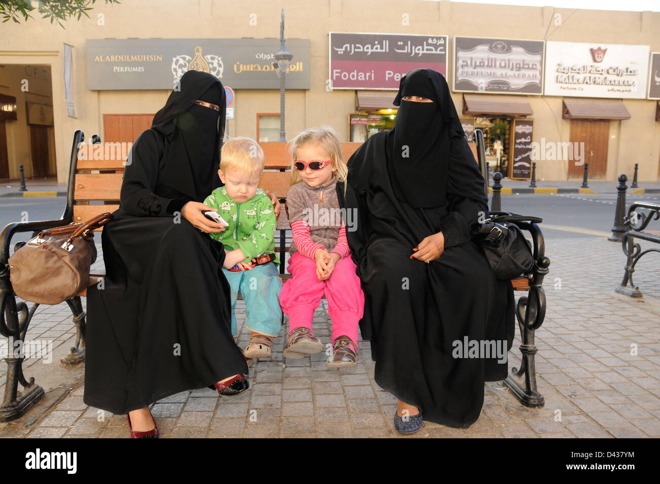 Due bambini turistiche con donne locali, Kuwait City Foto Stock