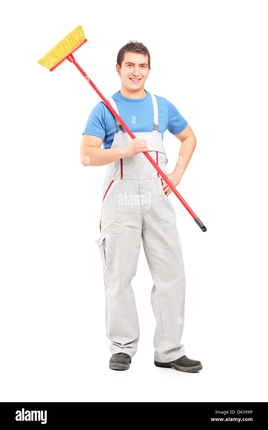 A piena lunghezza Ritratto di un fiducioso il detergente in un uniforme con una scopa isolata contro uno sfondo bianco Foto Stock