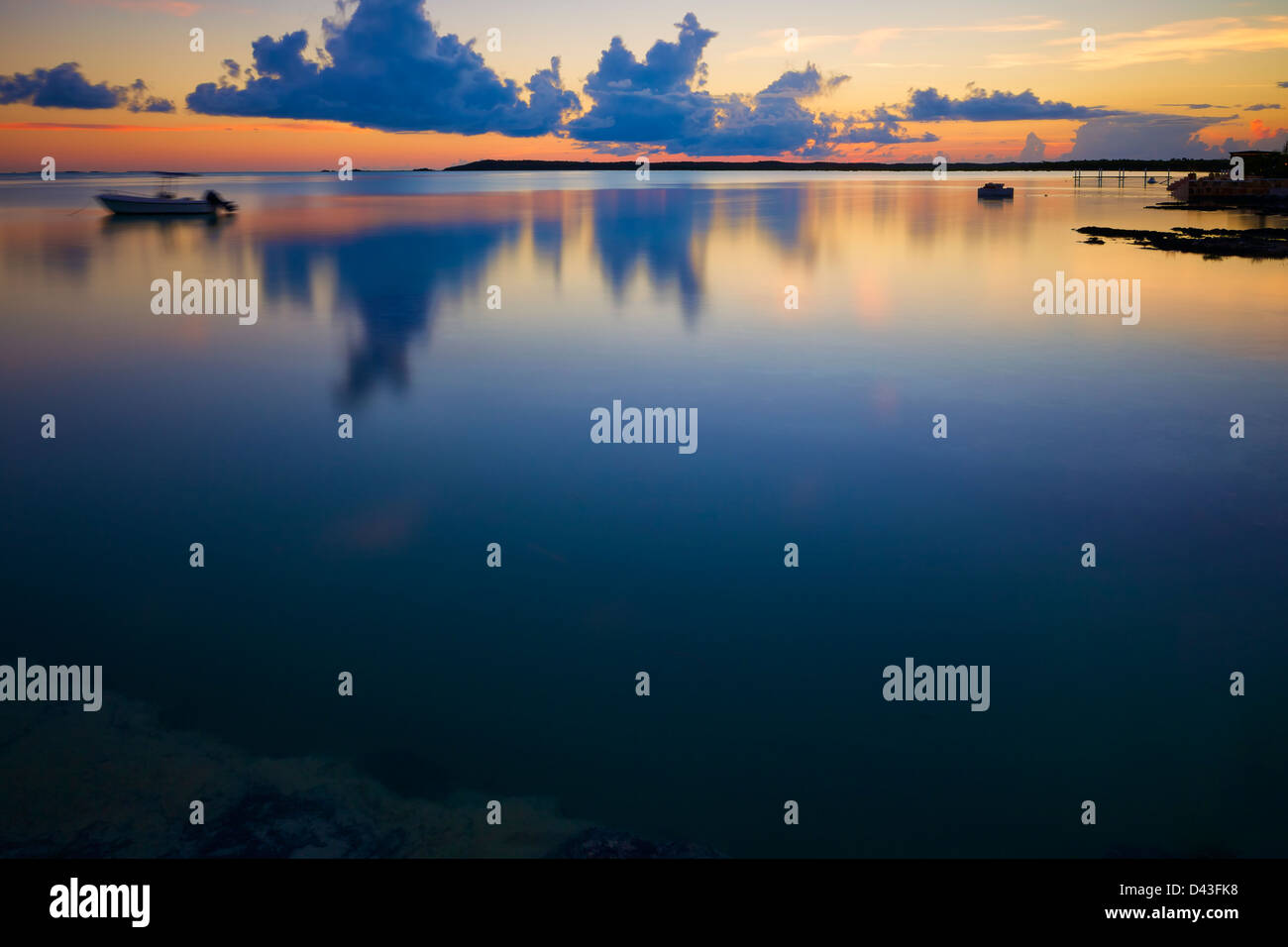 L'acqua di una piccola baia a Exuma Island, Bahamas, ricade totalmente ancora come il sole tramonta. Foto Stock