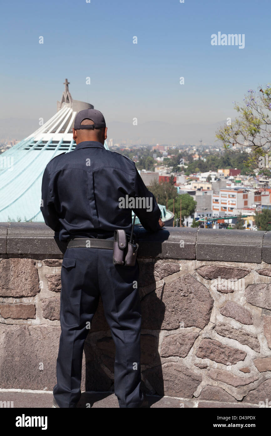 Una guardia di sicurezza rileva il movimento di turisti al di sotto, attorno alla Basilica di Guadalupe. Foto Stock