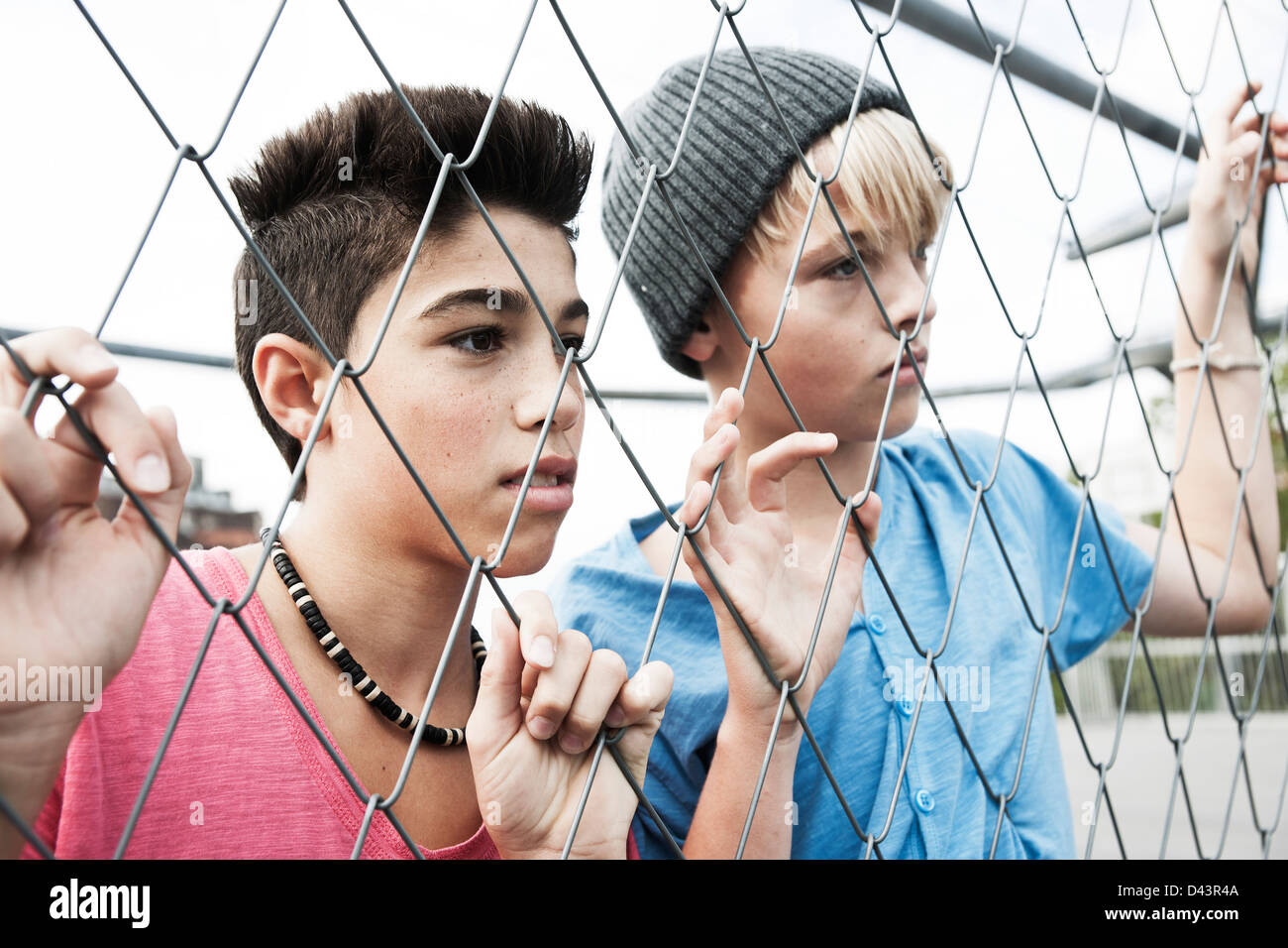 Due ragazzi cercando attraverso la catena collegamento recinto, Mannheim, Baden-Württemberg, Germania Foto Stock